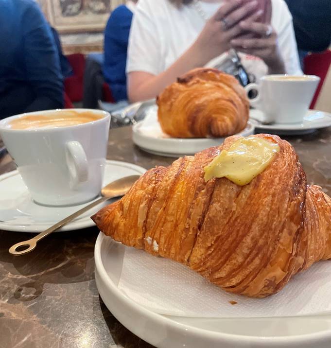 Afbeelding met croissant, persoon, Fastfood, bakwarenDoor AI gegenereerde inhoud is mogelijk onjuist.